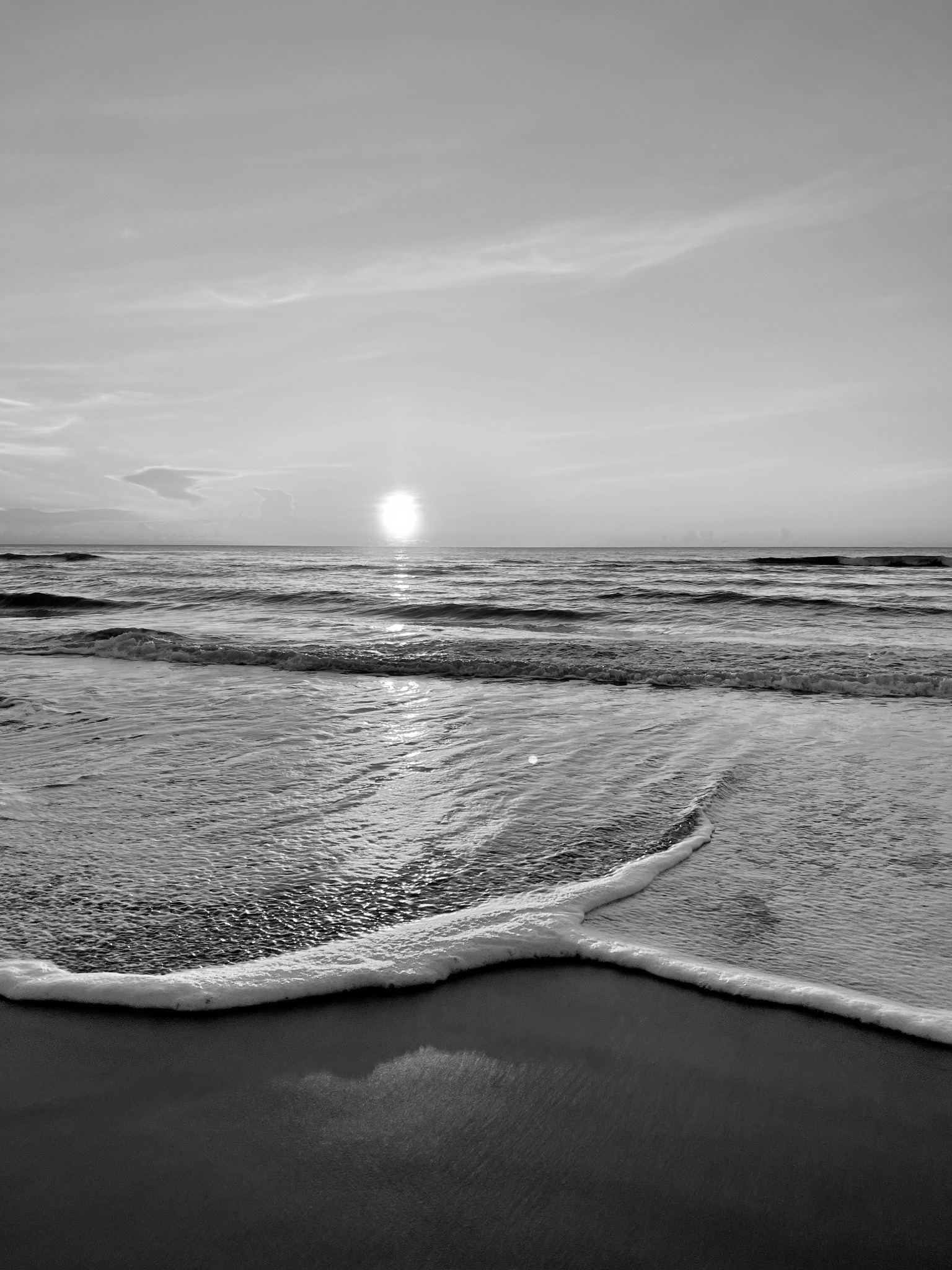 Black-and-white photograph of waves rolling onto Coquina Beach at sunset